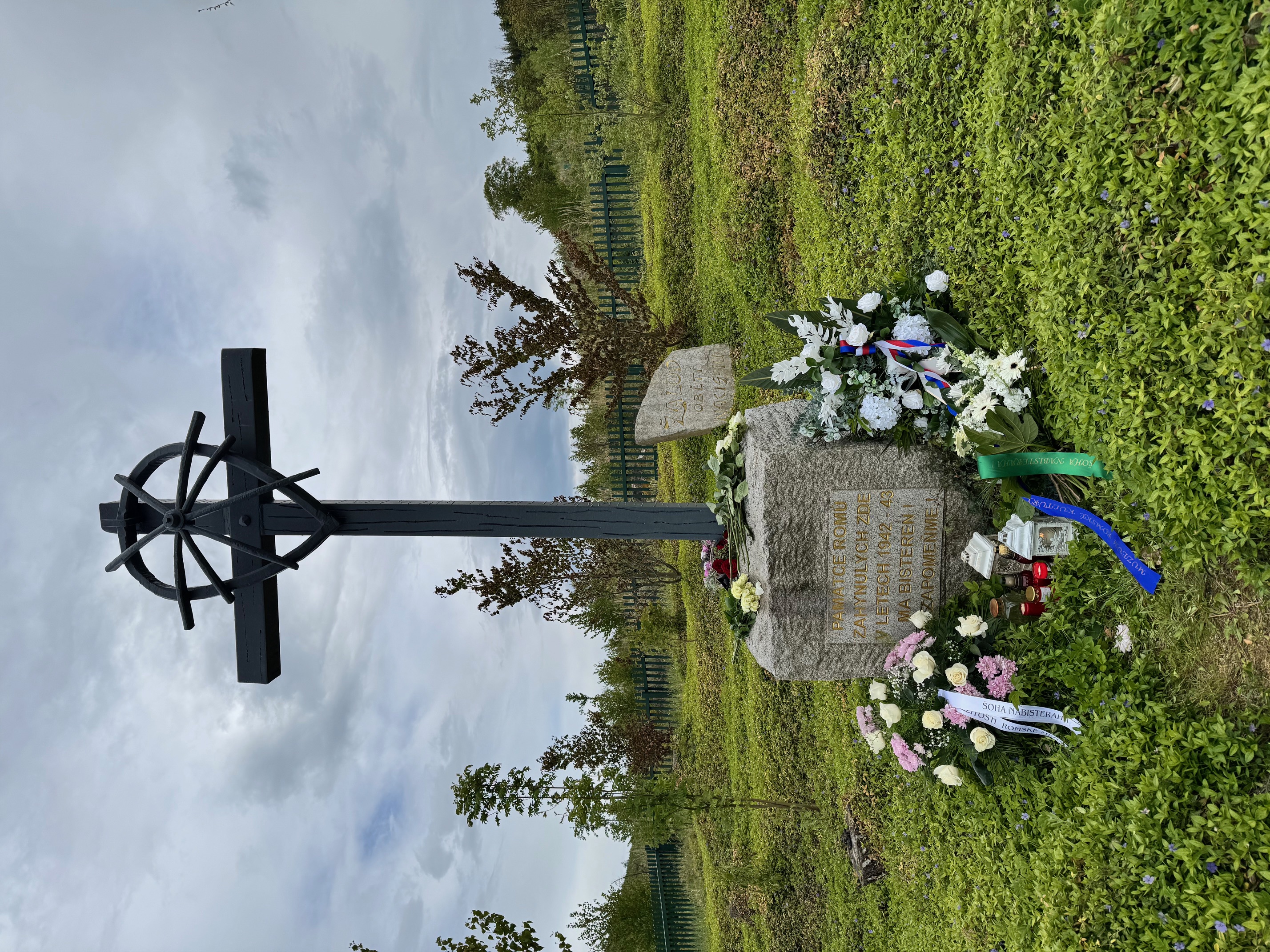 Pomnik Pamięci o Holokauście Romów i Sinti w Hodonínie u Kunštátu, otoczony kwiatami i zniczami złożonymi przez uczestników ceremonii.